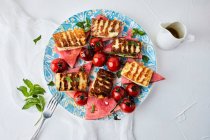 Wassermelone, gegrillte Halloumi und Kirschtomaten mit Olivenöl beträufelt, vermischt mit frischer Minze und Basilikum — Stockfoto