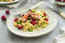 Couscous salad with fresh sweet cherries and fried duck breast — Stock Photo