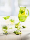 Hausgemachte Limonade in Gläsern und Kannen mit Limetten und Basilikum — Stockfoto