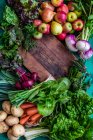 Legumes orgânicos e frutas com tábua de corte de madeira — Fotografia de Stock