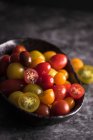 Cherries tomatoes in a black bowl — Stock Photo