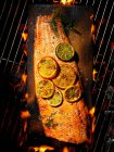 Cedar-planked salmon with citrus and herbs over flames and coals - foto de stock