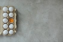 Huevos en contenedor de papel sobre superficie de hormigón - foto de stock