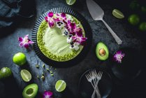 Авокадо и лаймовый чизкейк, украшенные цветами и фисташками — стоковое фото