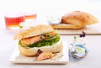 Sesame salmon burger with wasabi cream, salad and radish cress — Stock Photo
