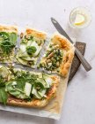 A pizza topped with green vegetables and nuts — Stock Photo