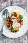 Grilled organic peaches with buffalo mozzarella and spoon in plate — Stock Photo
