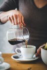 Nahaufnahme der Hand einer Frau, die Kaffee in eine Kaffeetasse gießt — Stockfoto