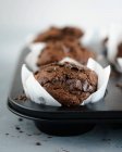Muffins de chocolate em casos de bolos brancos — Fotografia de Stock