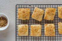 Biscotti quadrati su rastrelliera di raffreddamento e piccola boccia di zucchero di canna — Foto stock