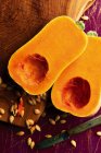 Zucca di butternut dimezzata con semi sparsi su un tagliere — Foto stock