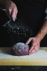 Purple loaf of spelt aronia berry powder bread being dusted with flour — Stock Photo