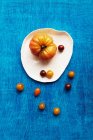 Verschiedene Tomatensorten auf einem Teller vor blauem Hintergrund — Stockfoto