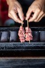 Hands holding skewers on japanese grill — Stock Photo