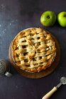 Apple pie with round knife and fresh apples — Stock Photo