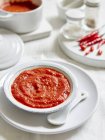Червоний томатний соус у скляній мисці на білому фоні — стокове фото
