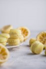 Mini lemon macarons with squeezed lemons on table — Stock Photo