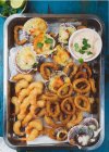 Bandeja caliente de mariscos: Anillos de calamares fritos, Osteones al horno y camarones fritos al horno con salsa - foto de stock