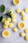 Mini lemon macarons with green leaves and squeezed lemons — Stock Photo