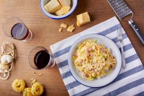 Pastas caseras Carbonara con queso parmesano y copas de vino tinto - foto de stock