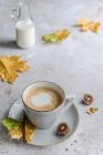 Cappuccino avec un cœur en mousse de lait entouré de feuilles d'automne — Photo de stock