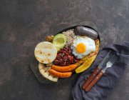 Bandeja paisa - Vientre de cerdo frito colombiano, budín negro, salchicha, arepa, frijoles, plátano frito, huevo de aguacate y arroz - foto de stock