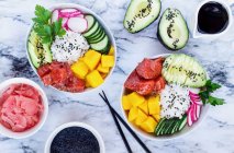 Hawaiian poke bowls with basmati rice, mango, raw salmon, avocado, radishes, cucumber, pickled ginger and black sesame — Fotografia de Stock