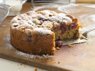 Cherry cake dusted with icing sugar, a piece cut — Foto stock