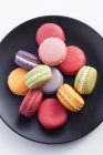 Colorful macarons on black plate, top view — Stock Photo