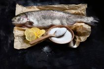 Trucha entera de salmón fresco con sal y limón - foto de stock