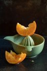 Squeezed orange slices and ceramic squeezer — Stock Photo