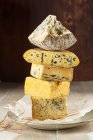 Selección de quesos azules apilados sobre papel - foto de stock
