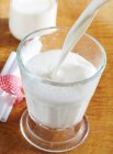 Latte fresco e freddo versato nel bicchiere — Foto stock