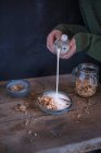 Человек, наливающий молоко в миску мюсли — стоковое фото