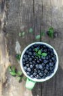 Myrtilles sauvages en tasse sur fond en bois — Photo de stock