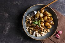 White mushrooms in garlic cream sauce with roasted young potatoes — Stock Photo