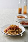 Koshari Traditional Egyptian dish, vegan mixed rice, pasta, lentils, with caramelized onions and tomato chili sauce — Stock Photo