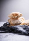 Pita bread stacked on a tea towel against a grey background — Stock Photo