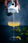 Bartender pouring cocktail in glass with lemon and mint — Stock Photo