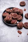 Biscuits végétaliens au chocolat et noix de pécan dans une assiette et sur une surface en pierre — Photo de stock