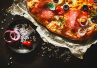 Uma pizza coberta com salame, azeitonas, peperoni e cebola (close-up) — Fotografia de Stock