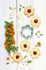 Las galletas las flores con la confitura de frambuesa y la rama de las hojas y las bayas - foto de stock