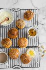 Homemade mini buns on cooling rack with cream and jam — Stock Photo