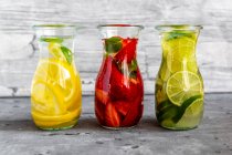 Bottiglie di bevande infuse con fragole, lime e limone — Foto stock
