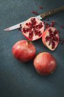 Granatäpfel, ganz und halbiert auf dem Tisch mit Messer — Stockfoto