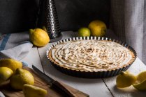 Lemon meringue tart surrounded with lemons — Stock Photo