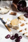Tabla de quesos con brie cubierto con panal, galletas saladas, nueces, pistachos, uvas y vino blanco - foto de stock