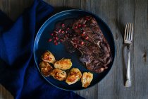 Gegrilltes Lammkotelett mit roter Granatapfelsoße und in der Pfanne gebratenen Rosenkohl mit Speck und Cashewnüssen — Stockfoto