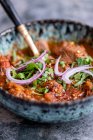 A bowl of beef curry with red onions and coriander — Stock Photo