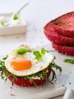 Sunny side up with rucola on a beet bread bun — Stock Photo
